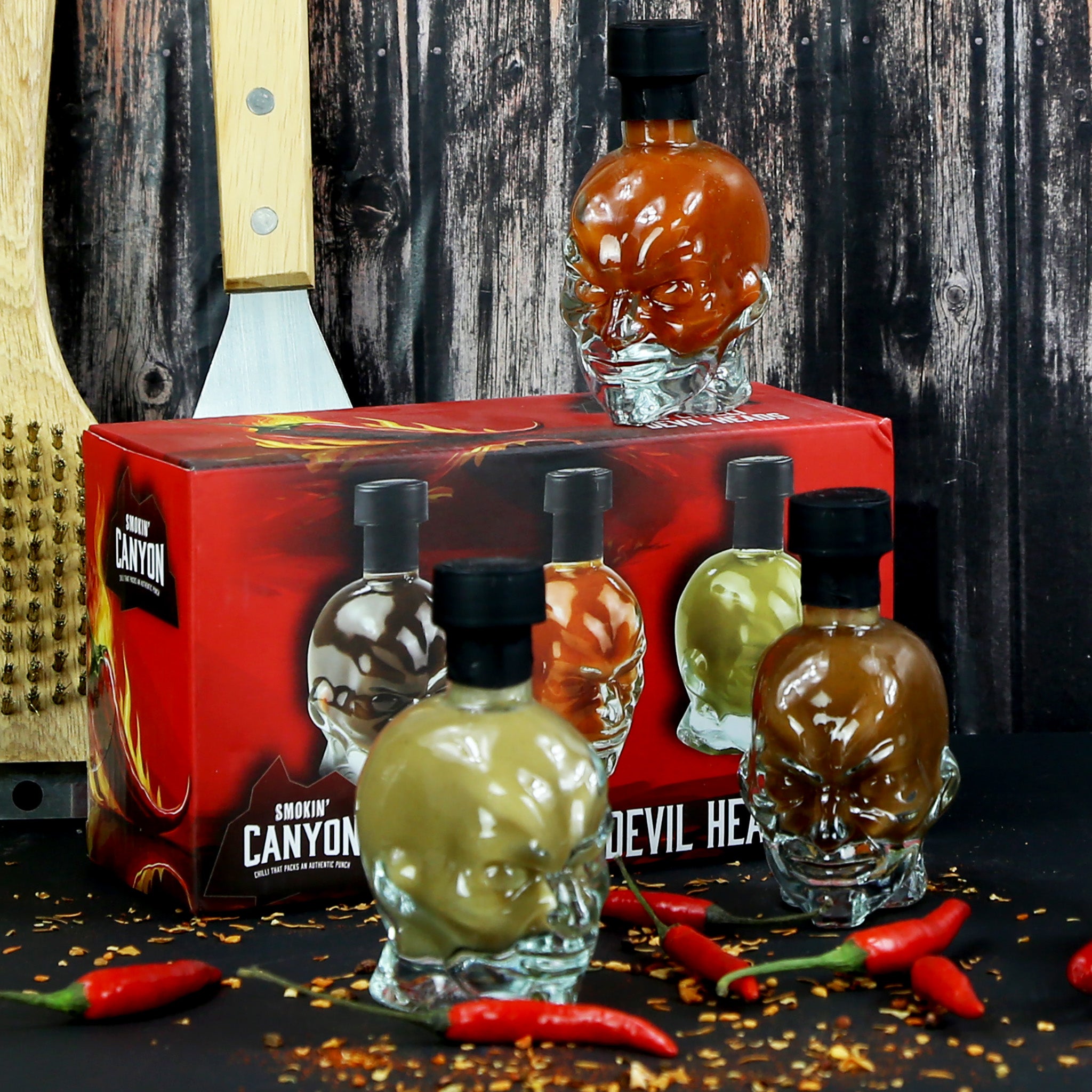 3 devil head shaped glass bottles with hot chilli sauce