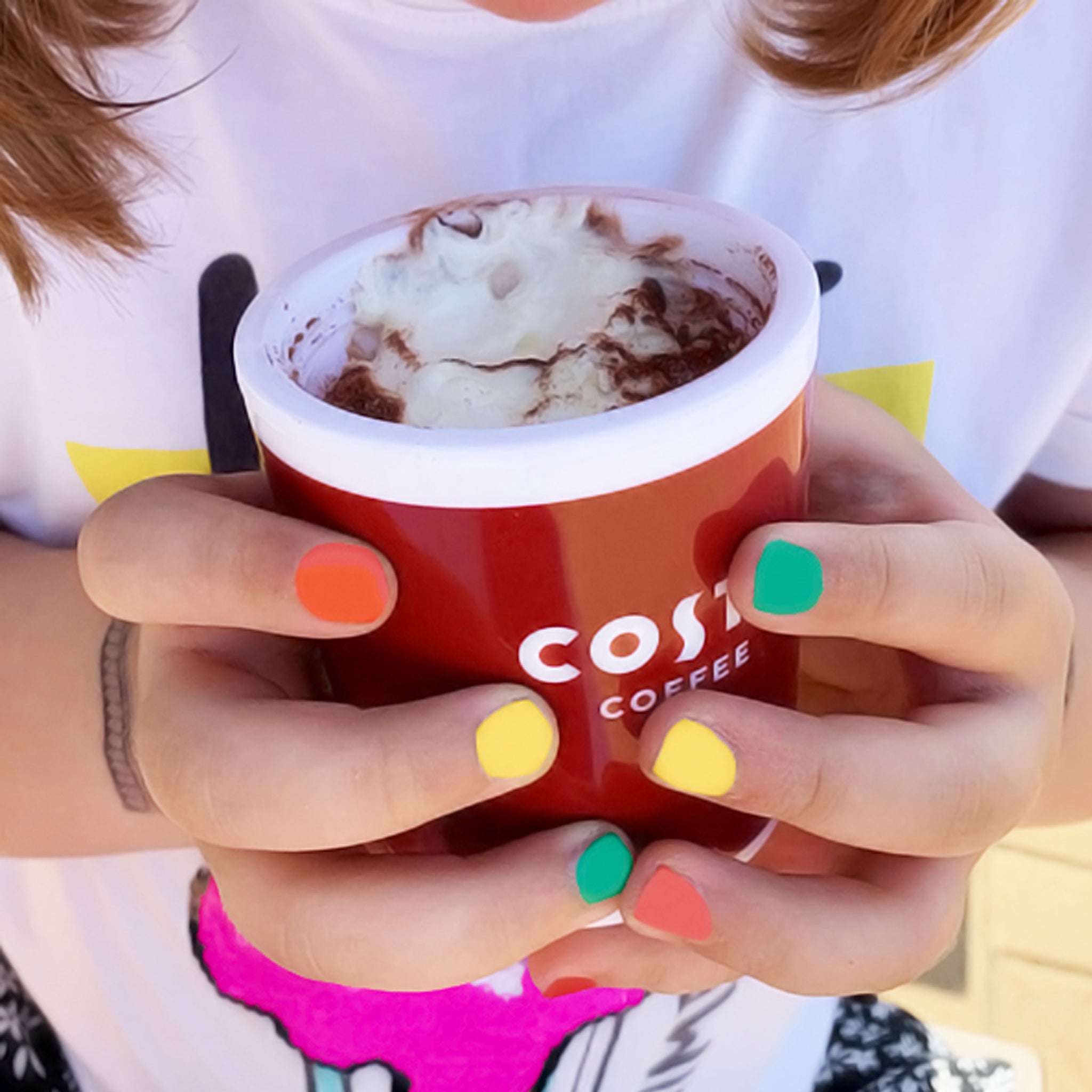 Costa babyccino plastic cup held in two hands