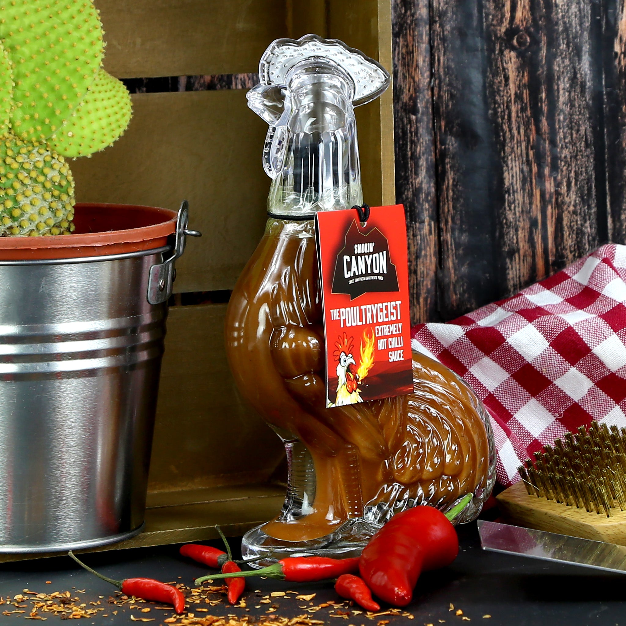 Fiery hot chilli sauce presented in a glass bottle shaped like a rooster